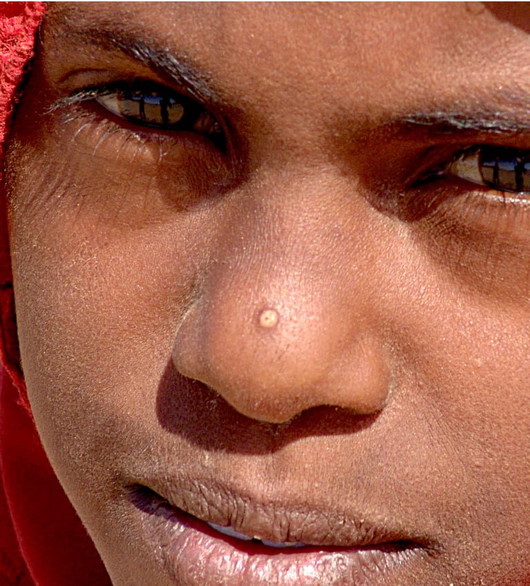 Primo piano del volto di una donna nubiana con velo rosso, deserto di Bayuda